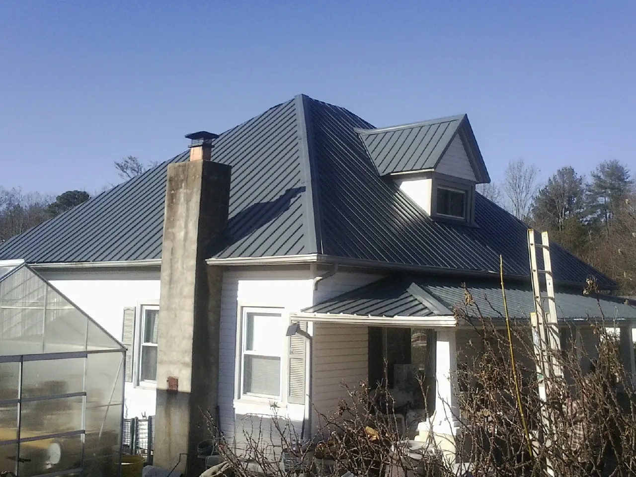 Dark blue standing seam metal roof on a white farmhouse with dormer — Slate & Tile Roof Repair by Roofing Brothers in Tallassee