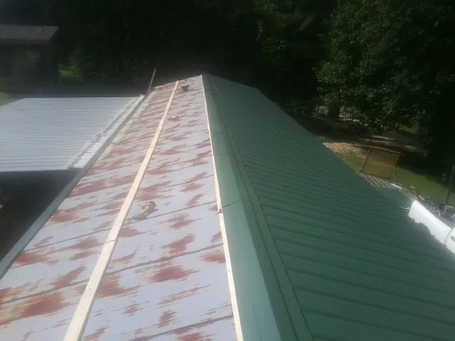 Old rusted panels beside newly installed green metal roofing — Wind Damage Roof Repair by Roofing Brothers in Tallassee